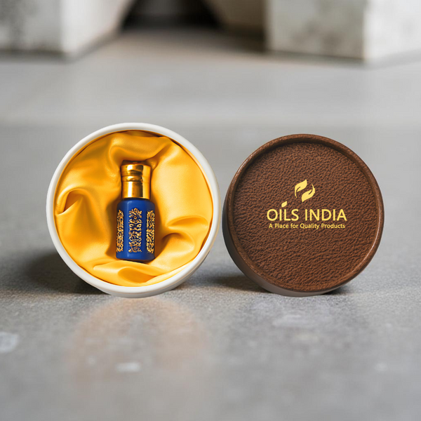 Blue perfume bottle in a white box with gray interior, next to a brown leather cover with 'Oils India In' branding.