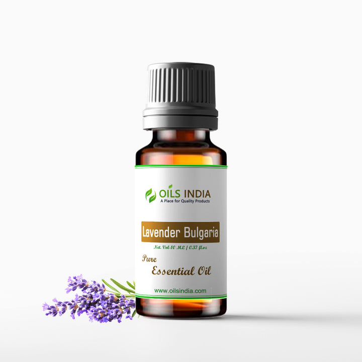 A bottle of Pure Essential Oil branded by Oils India, labeled 'Lavender Bulgaria'. The bottle is accompanied by a small sprig of lavender flowers.