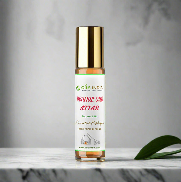 Roll-on bottle of Oils India Dehnila Oud Attar on a marble surface with a blurred plant and wall in the background.