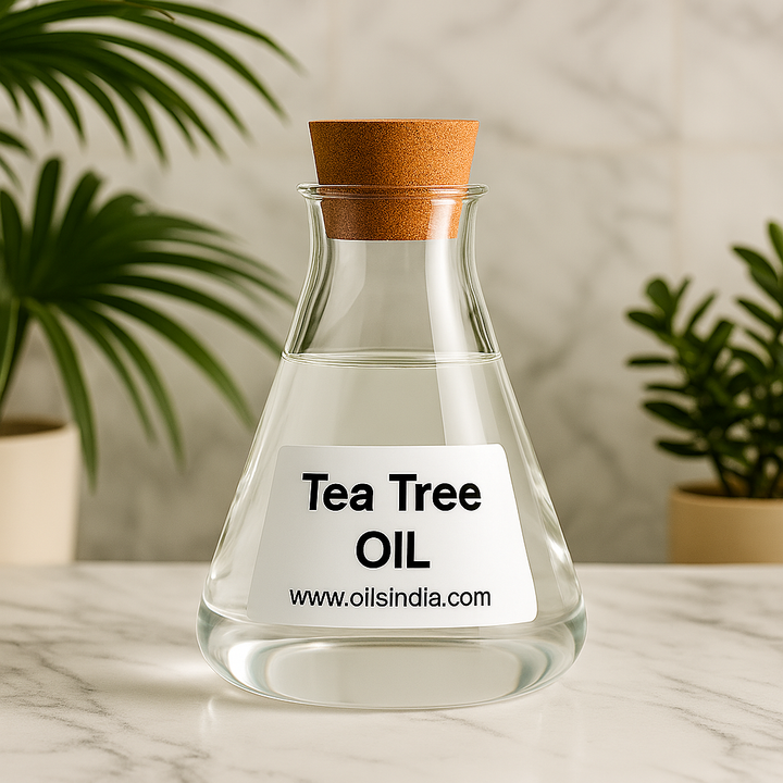 Clear glass bottle of tea tree oil with a cork lid on a marble surface, plants in the background by Oils India.
