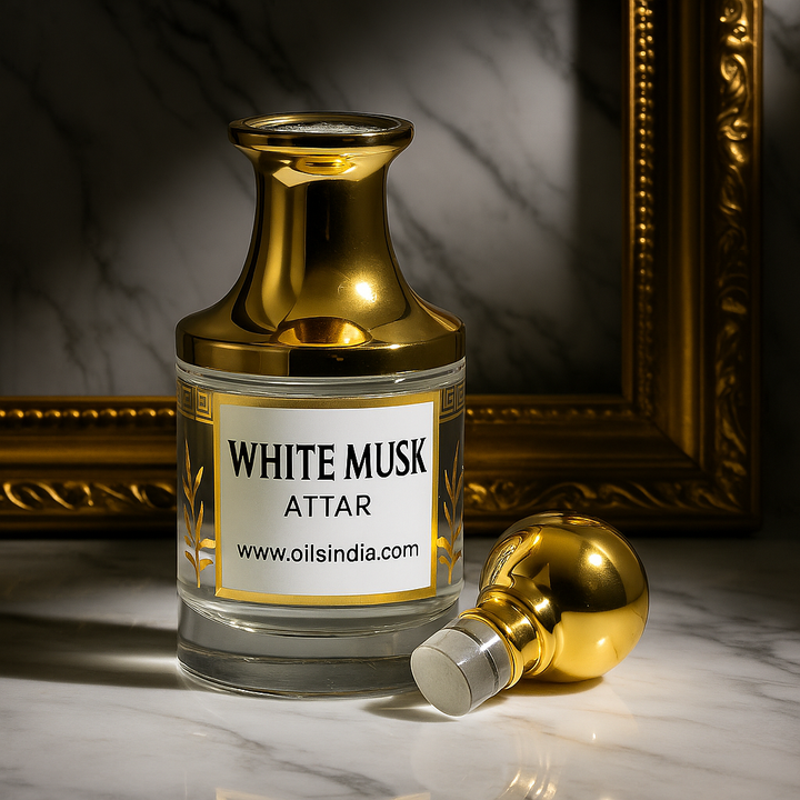 Gold and glass bottle labeled 'White Musk Attar' on a marble surface with a gold frame in the background by Oils India.